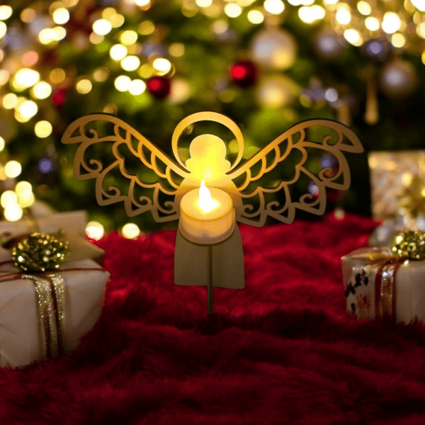 Laser-cut wooden angel tea light holder glowing warmly on a Christmas-decorated table with festive gift boxes and holiday lights in the background.